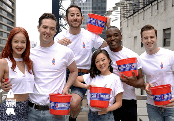 A Group Holding Red Buckets for Broadway Cares Equity Fights AIDS