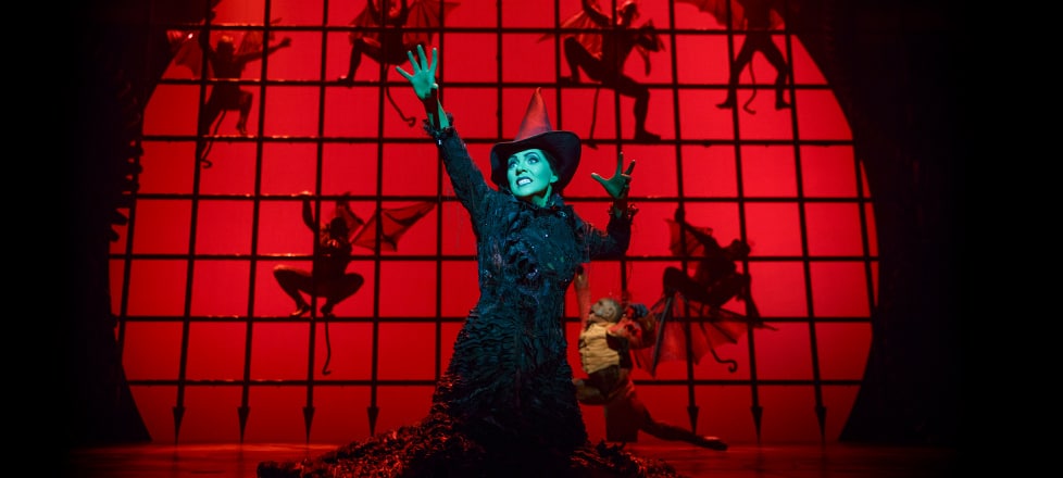 Elphaba Conjuring a Spell With Flying Monkeys Climbing a Grid in the Background